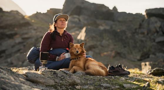 Kvinna i sovsäck tar en fikapaus tillsammans med sin hund.