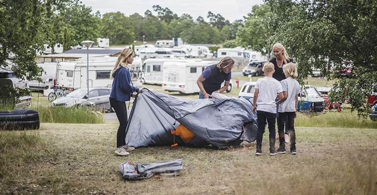 Familj sätter upp sitt tält på en campingplats.